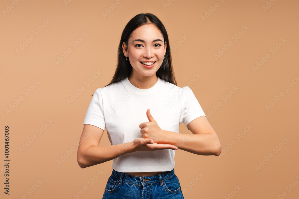 Smiling Asian woman gesturing with hand looking at camera isolated on beige background Smiling Asian woman gesturing with hand looking at camera isolated on beige background