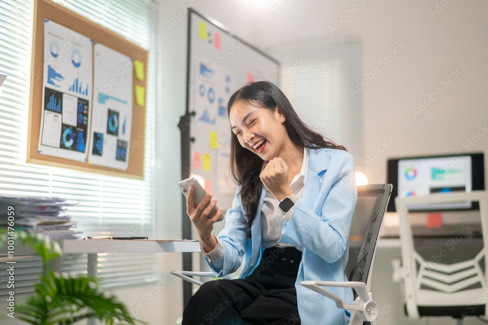 A woman is sitting at a desk with a cell phone in her hand A woman is sitting at a desk with a cell phone in her hand