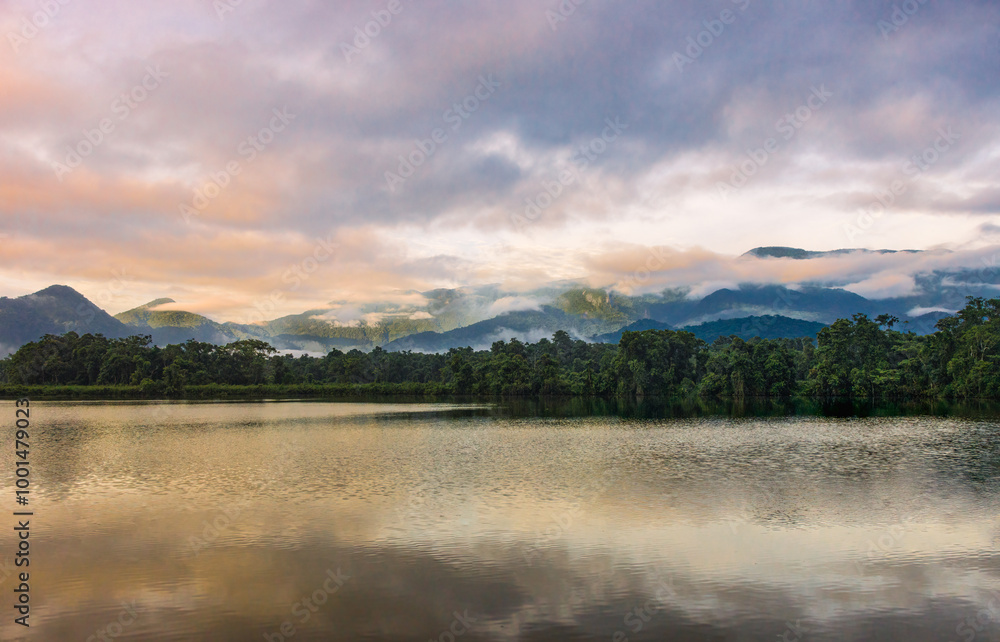 The warm dawn lighting the pond, the forest, and the mountain range The warm dawn lighting the pond, the forest, and the mountain range