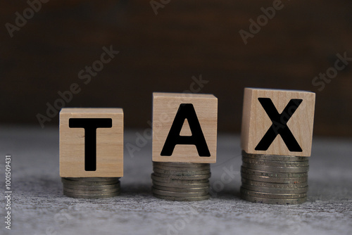 Tax text on the wooden block stacked on coins. the bigger wood blocks stack on the small ones, tax planning, tax at a high level photo