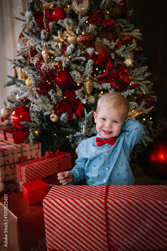 Portrait of happy cheerful little boy wearing tie bow standing behind gift. Greeting card or cover photo