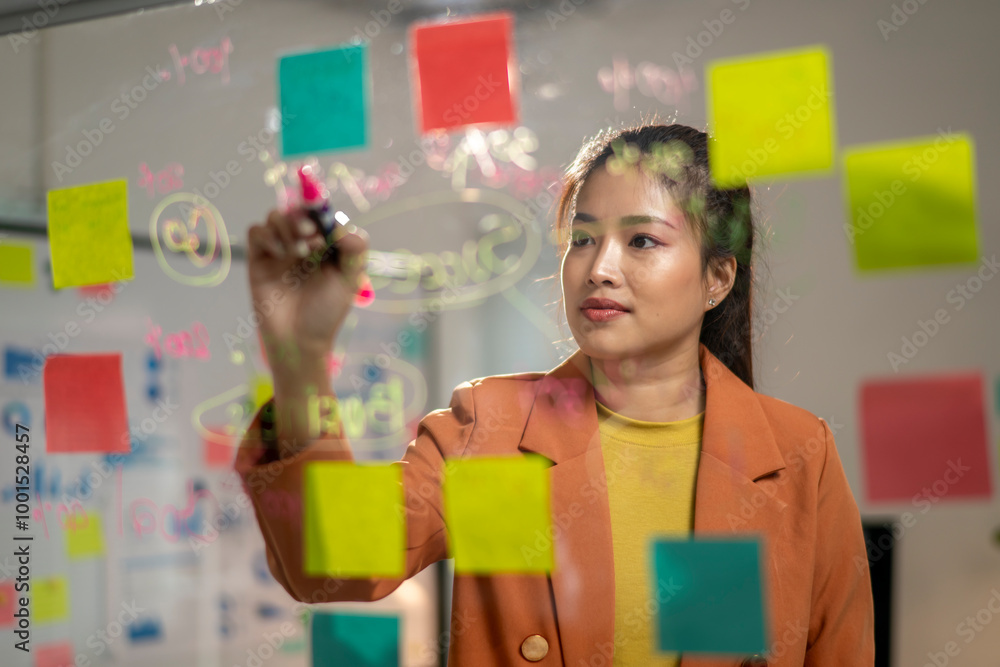 © Wasana - A woman is drawing on a white board with colorful markers © Wasana - A woman is drawing on a white board with colorful markers