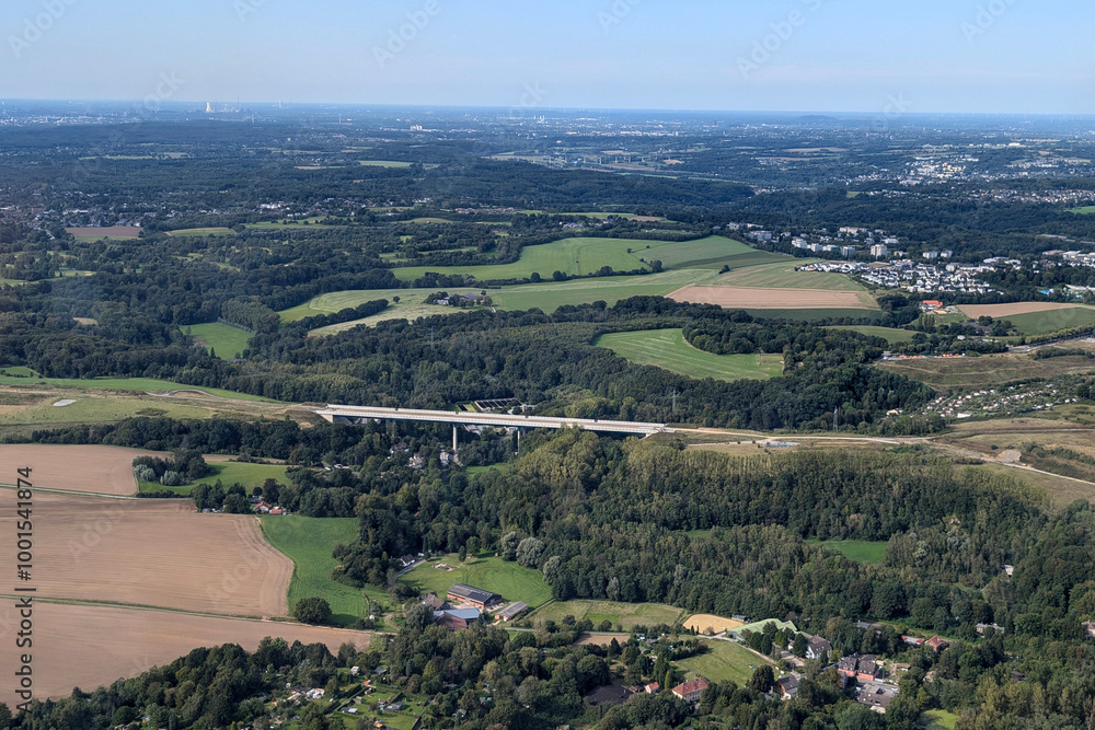 view from above of the fields, forests and highway bridge angertal A44 with heiligenhaus in the background on a sunny day view from above of the fields, forests and highway bridge angertal A44 with heiligenhaus in the background on a sunny day