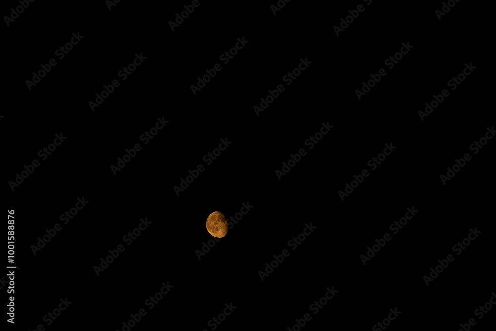 a reddish-yellow moon against a dark background
a reddish-yellow moon against a dark background