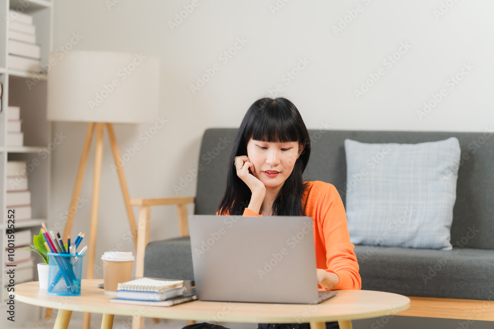 Focused on the Task: A young woman works diligently on her laptop, engrossed in her work. The comfortable setting and relaxed posture suggest a sense of ease and focus. Focused on the Task: A young woman works diligently on her laptop, engrossed in her work. The comfortable setting and relaxed posture suggest a sense of ease and focus.