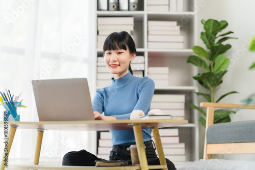 Working from Home: A young woman smiles confidently as she works on her laptop from the comfort of her home office, showcasing the modern trend of remote work and a flexible lifestyle. 