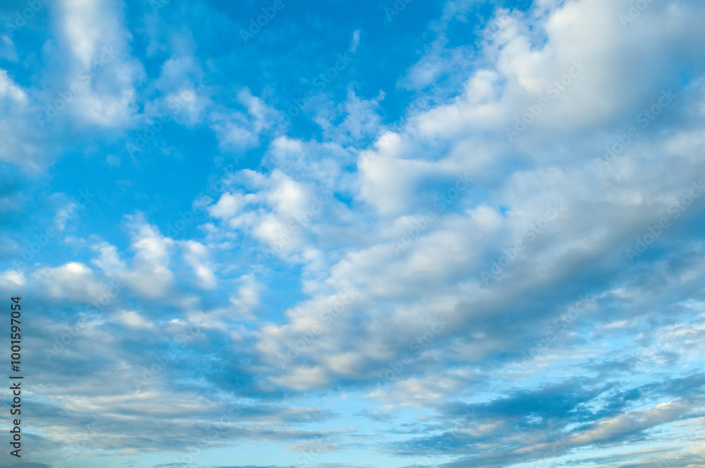 Cloudy blue sky with fluffy clouds lit by sunlight - natural cloudy sky background, panoramic view of blue cloudy sky Cloudy blue sky with fluffy clouds lit by sunlight - natural cloudy sky background, panoramic view of blue cloudy sky