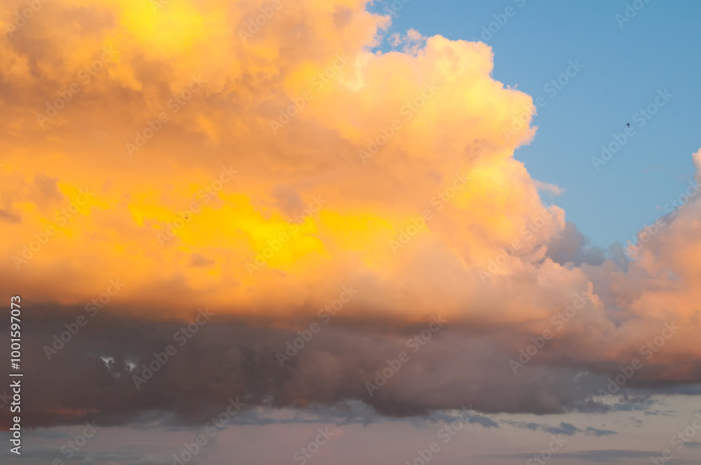 Sunset sky background with fluffy golden clouds in the sunset sky. Vast sunset sky background in dramatic tones