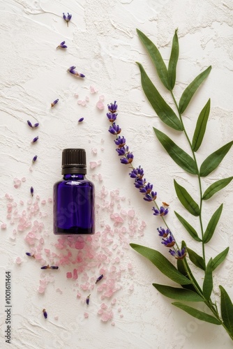 Lavender essential oil bottle surrounded by flowers and leaves on a white sur...