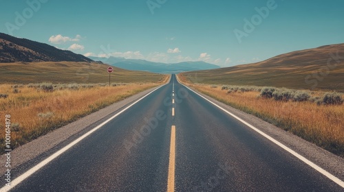 Long highway stretching through scenic mountains under a bright blue sky during daytime