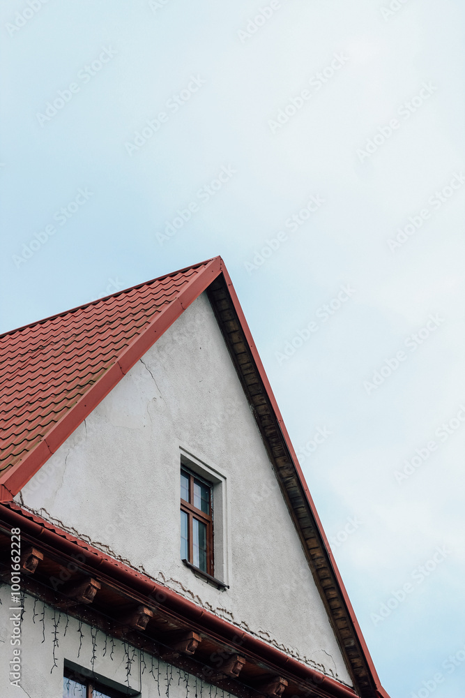 orange roof of a modern house with windows on the background of a gray cloudy sky orange roof of a modern house with windows on the background of a gray cloudy sky