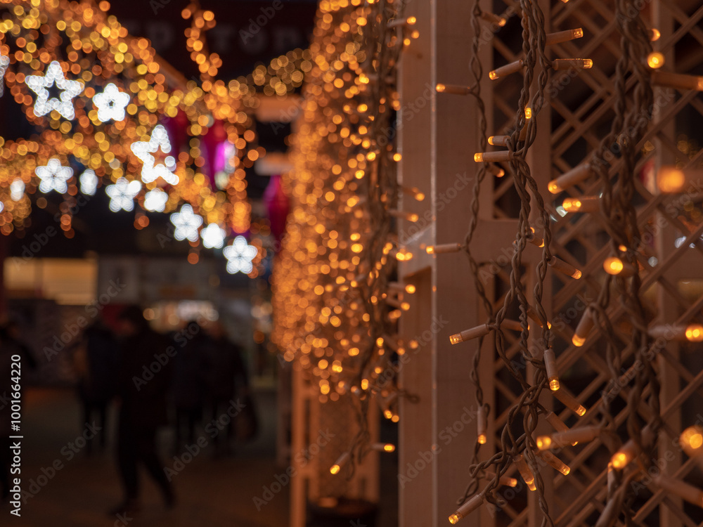 Christmas and New Year holidays decorations of streets with trees and shops with multicolored christmas string fairy lights glowing in the darkness outdoors. Winter holidays celebration concept.