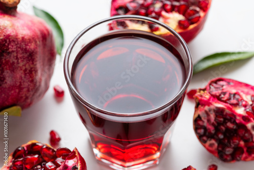 Glass of fresh pomegranate juice with pomeganate fruits on white marble background. Healthy refreshing drink photo