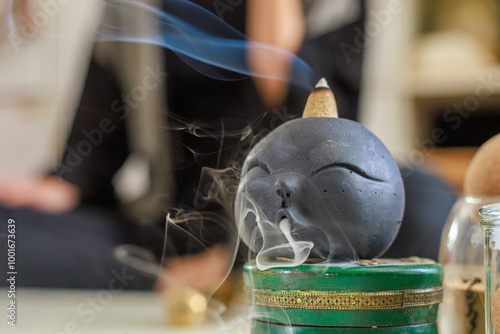 Smoke comes out of a burnt incense cone in the beautiful incense burner. photo