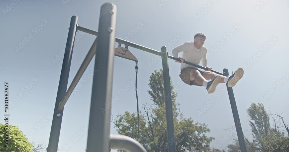 A fit young man exercising on a pull up bar at an outdoor gym. He is working out and training his muscles. A fit young man exercising on a pull up bar at an outdoor gym. He is working out and training his muscles.