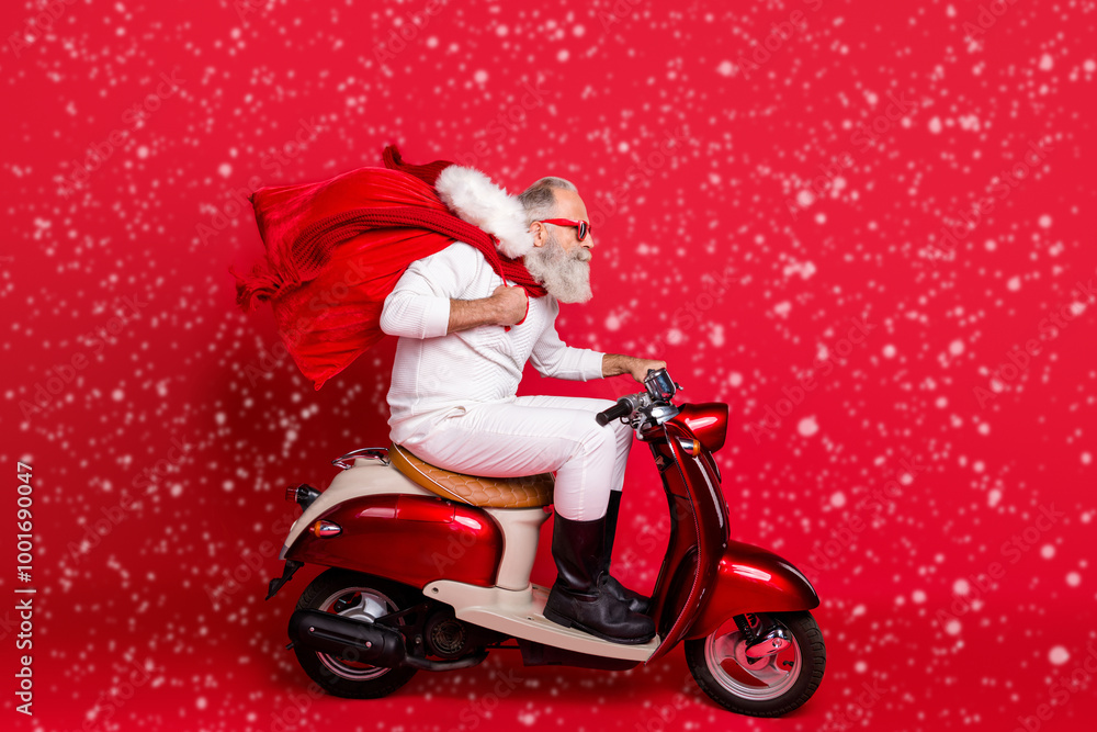 Profile side view of nice bearded gray-haired Saint Nicholas riding motor delivering carrying desirable purchase things December wintertime isolated on bright vivid shine red background Profile side view of nice bearded gray-haired Saint Nicholas riding motor delivering carrying desirable purchase things December wintertime isolated on bright vivid shine red background