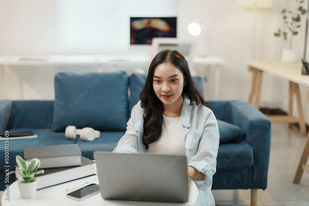Young asian woman is working from home, sitting on the floor and typing on her laptop computer Young asian woman is working from home, sitting on the floor and typing on her laptop computer