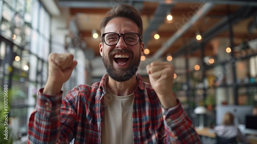 A motivated office worker celebrating a success with a fist pump in a bright open office space.