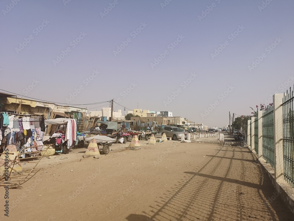 A bustling street filled with local vendors and vehicles in Nouakchott, Mauritania, under a clear sky in daytime A bustling street filled with local vendors and vehicles in Nouakchott, Mauritania, under a clear sky in daytime