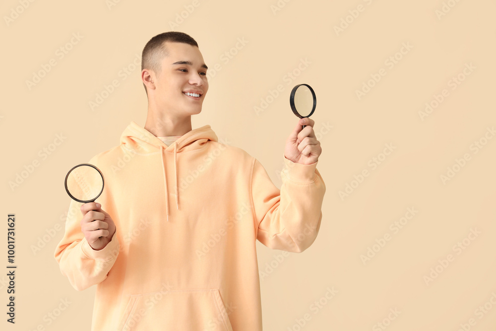 Young man with magnifiers on beige background Young man with magnifiers on beige background
