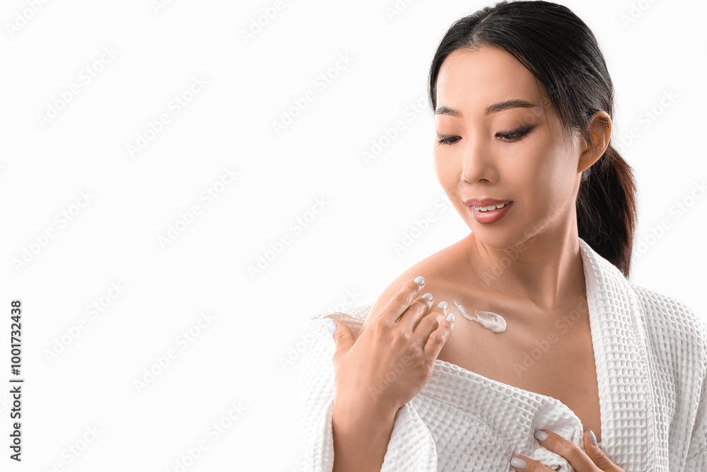 Beautiful Asian woman applying body cream against white background Beautiful Asian woman applying body cream against white background