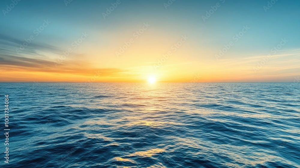 Obraz premium A stunning sunset over the vast ocean with a golden horizon and blue sky.