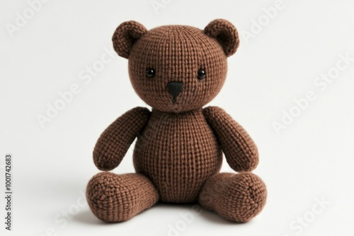 In white background, a knitted teddy bear lies down