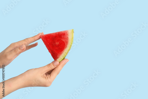 Female hands with slice of ripe watermelon on blue background photo