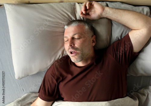 Photos Middle aged man sleeping and snoring, lying with closed eyes in comfortable bed in bedroom at home, above view