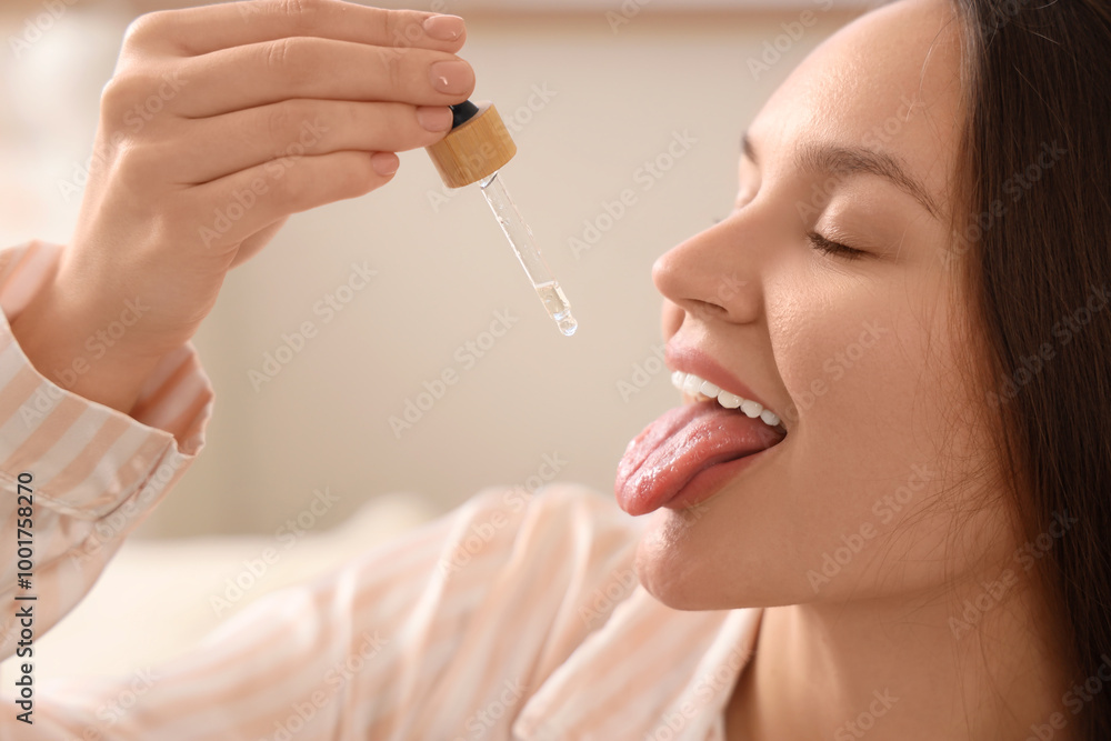 Young woman taking CBD oil in bedroom, closeup Young woman taking CBD oil in bedroom, closeup