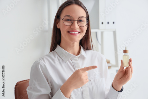 Young businesswoman pointing at bottle of CBD oil in office, closeup