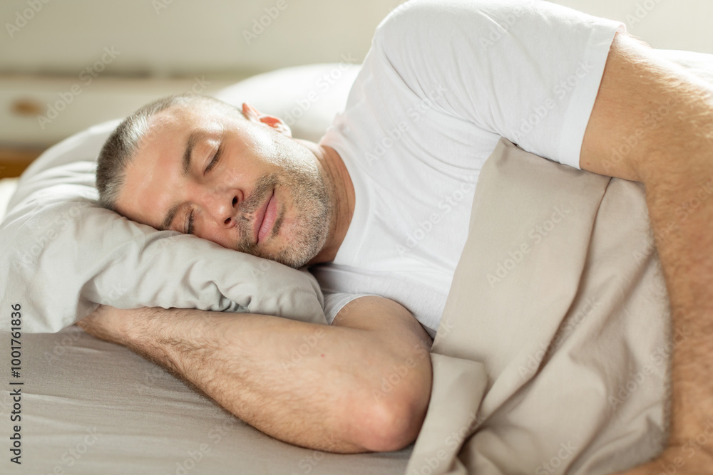 Asleep European middle aged man resting peacefully in comfortable bed, lying with closed eyes under blanket. Time to rest and nap concept