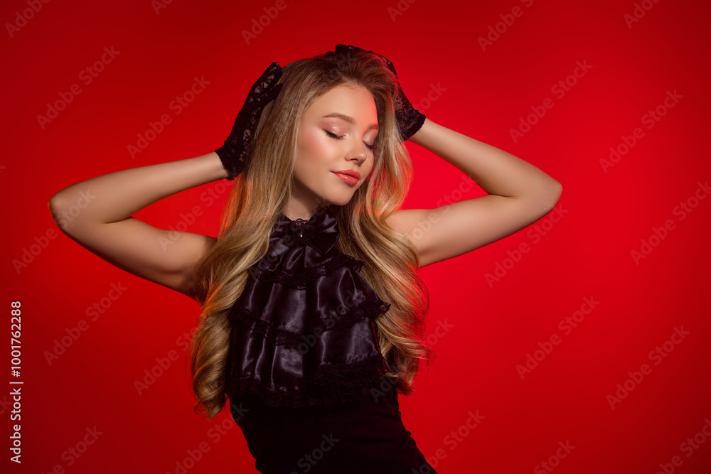 Photo of chic lovely girl close eyes touch hair prepare for halloween party wear black gown over red background Photo of chic lovely girl close eyes touch hair prepare for halloween party wear black gown over red background