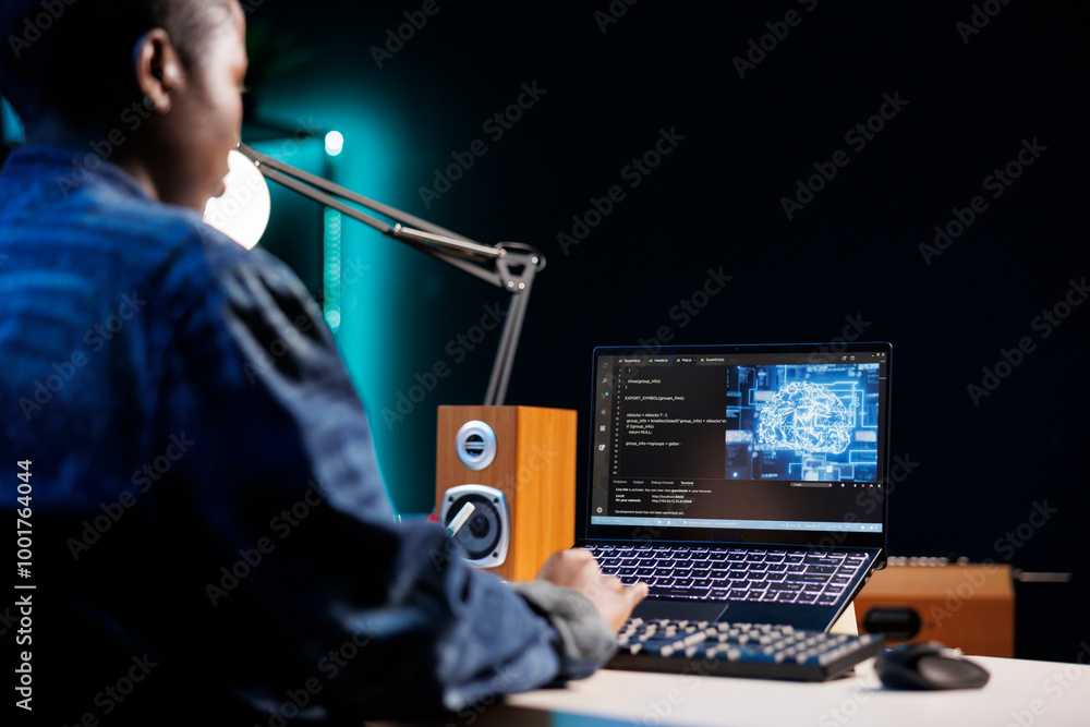 Professional female developer manages neural network at desk, working with code on laptop. Over the shoulder shot of african american freelancer developing cyber security, creating secure database. Professional female developer manages neural network at desk, working with code on laptop. Over the shoulder shot of african american freelancer developing cyber security, creating secure database.