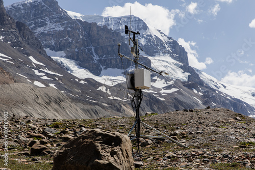 A detailed view of a weather monitoring station set against a backdrop of towering, snow-capped mountains, perfect for environmental data collection and scientific research photography.