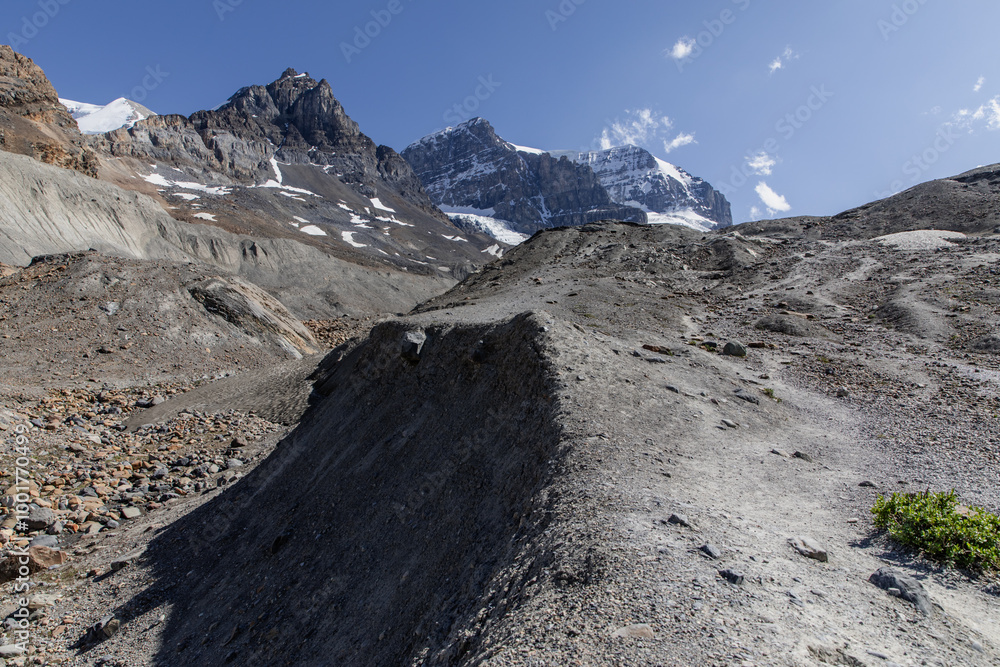 Fototapeta premium An eroded mountain path leading to awe-inspiring snowy peaks, capturing the essence of rugged highland terrains and the journey toward majestic natural beauty.