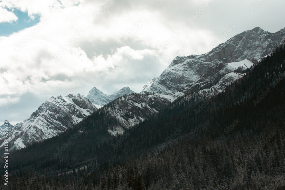 A mesmerizing view of snow-covered mountains under a cloudy sky, enveloping the viewer in the beauty of nature, with dense forest highlighting the serene landscape. A mesmerizing view of snow-covered mountains under a cloudy sky, enveloping the viewer in the beauty of nature, with dense forest highlighting the serene landscape.