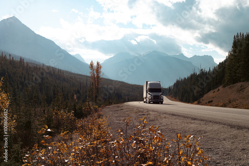 view of a truck rolling on a road in the mountains with sun light and clouds in the sky in autumn