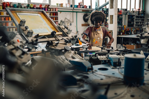 Smiling diverse printing shop worker silkscreen printing with squeegee