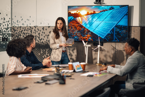 Ecology expert with solar panels having seminar with her diverse team. photo