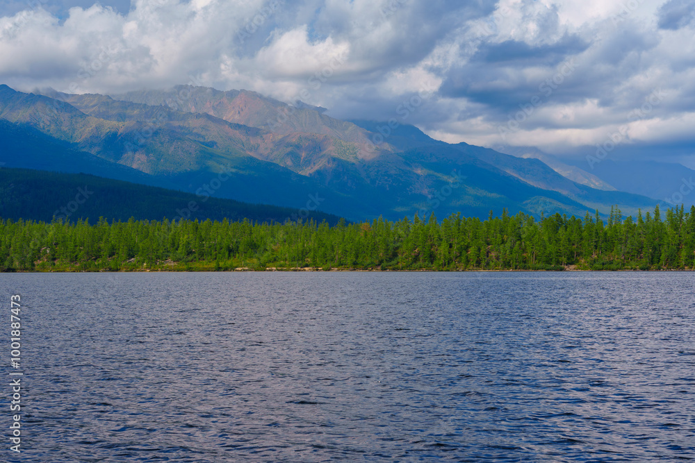 Fototapeta premium Lush green forest with mountain backdrop reflected in a calm lake
