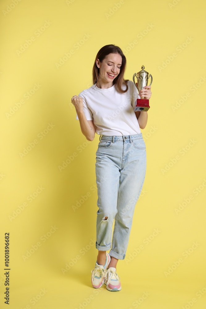 Happy winner with gold trophy cup on yellow background Happy winner with gold trophy cup on yellow background
