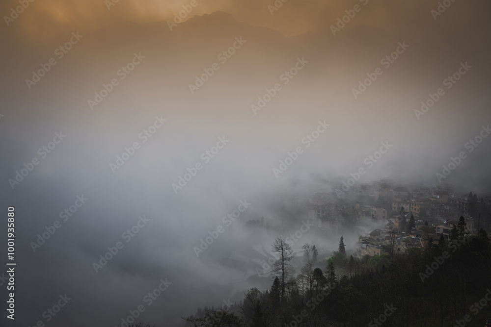 Orange sunrise sky at the rice terraces, dense fog and Duoyishu village, China Orange sunrise sky at the rice terraces, dense fog and Duoyishu village, China