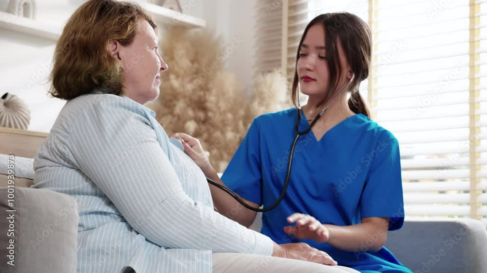 Caregiver young nurse woman examining elderly with stethoscope for checkup sitting on sofa in living room at home, nurse checkup patient about cardiac, patient and insurance, medical and health. Caregiver young nurse woman examining elderly with stethoscope for checkup sitting on sofa in living room at home, nurse checkup patient about cardiac, patient and insurance, medical and health.