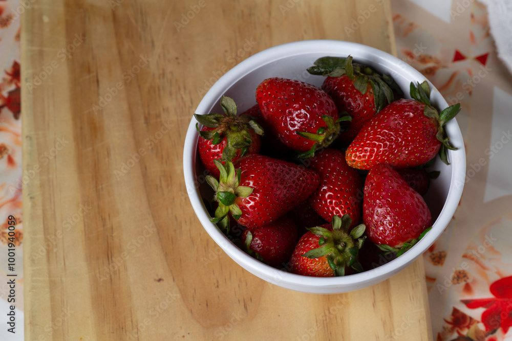 strawberries in a bowl on a wooden table strawberries in a bowl on a wooden table