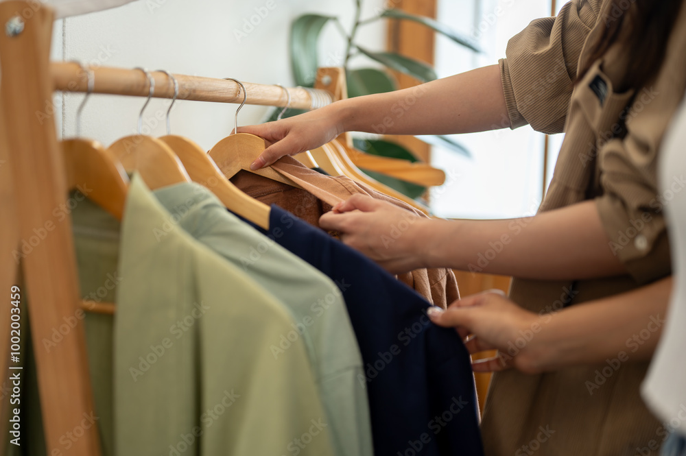 Obraz premium Females selecting clothes from a rack, enjoying their shopping experience together.