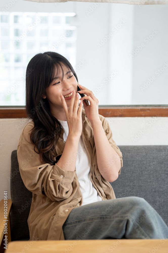 A woman is enjoying a conversation on the phone with her friend while sitting on a sofa indoors. A woman is enjoying a conversation on the phone with her friend while sitting on a sofa indoors.