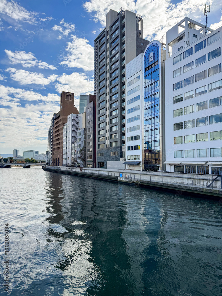 Fototapeta premium Modern skyscrapers reflected in a calm river ; A beautiful waterfront view with towering buildings