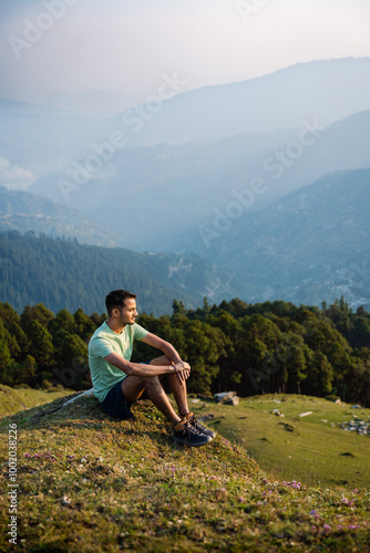 This Handsome male hiker smiling while seated on a mountain top in himachal pradesh india. 