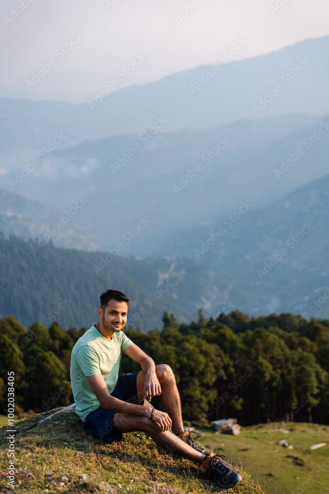 Naklejka premium This Handsome male hiker smiling while seated on a mountain top in himachal pradesh india. 